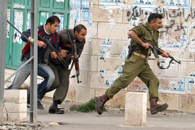 Palestinian security officers run during exchange of fire with Israeli troops in Bethlehem