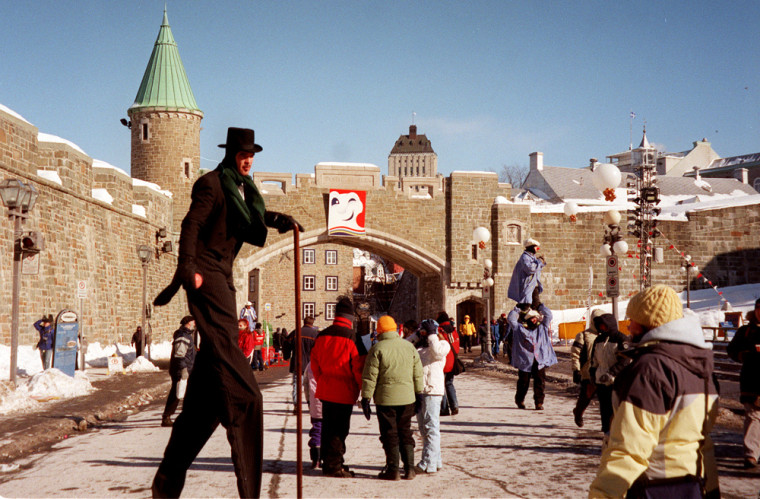 A man on stilts strolls by as visitors gather for winter carnival activities just outside the gate of Vieux Quebec in Quebec City, Canada, Feb. 15, 2003. Colorful characters fill the cobblestone streets for this annual festival.