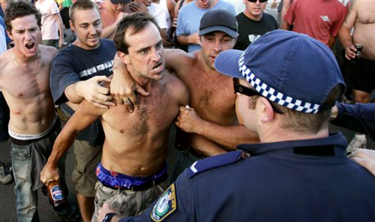 A man threatens police at Cronulla Beach in Sydney, Australia, Sunday, Dec. 11, 2005, after ethnic tensions erupted into running battles between police and a mob of thousands of youths, many chanting racial slurs. At least six people were arrested and several injured in alcohol-fueled fights at the beach. (AP Photo/Rob Griffith)