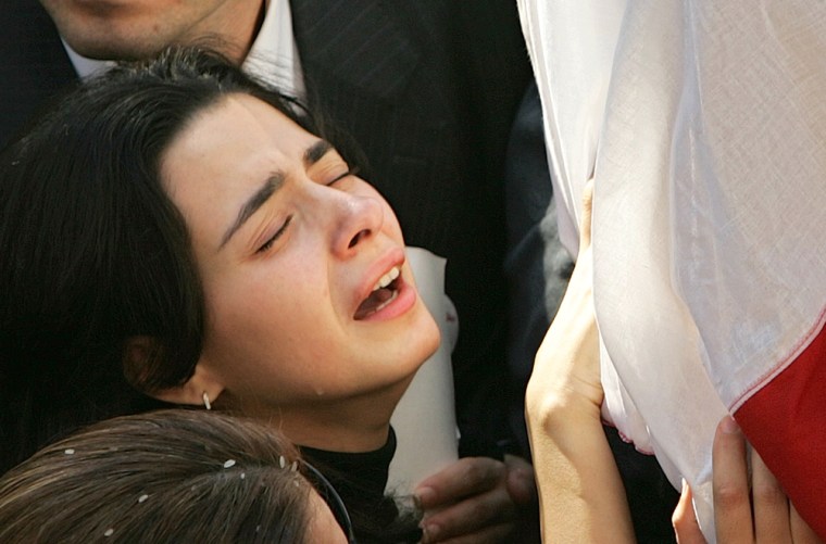 Nayla Tueni, daughter of slain anti-Syrian journalist and legislator Gibran Tueni, mourns as she lays her hand on her father's coffin, in the Beirut district of Ashrafieh, Lebanon, Wednesday, Dec. 14, 2005. Thousands of flag-waving Lebanese, Christians and Muslims, bid farewell to their leading newspaper editor Gibran Tueni, marching behind his coffin Wednesday in a display of anger against Syria that has been blamed for the car bombing which killed him Monday. (AP Photo/Hussein Malla)