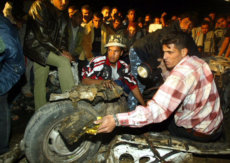 Palestinians examine wreckage of car after explosion in southern Gaza Strip
