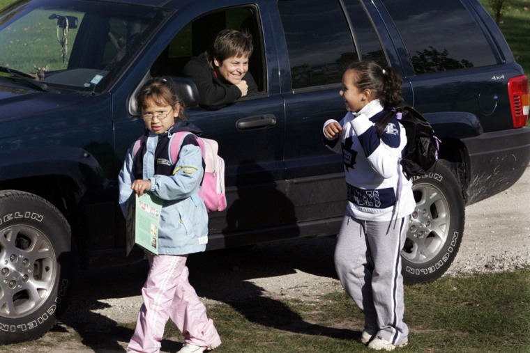 Ada Lockridge greets Shyanna Joseph, left, and her sister Joselyn Joseph as they arrive home from school on the Aamjiwnaang First Nation Reserve in Canada, Oct. 21, 2005. For nearly half a century, the reserve land across the U.S.-Canada border from Port Huron, Mich., has been almost completely surrounded by Canada's largest concentration of petrochemical manufacturing.  (AP Photo/Carlos Osorio)