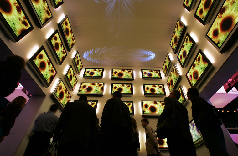 Attendees look up at plasma televisions during Consumer Electronics Show in Las Vegas