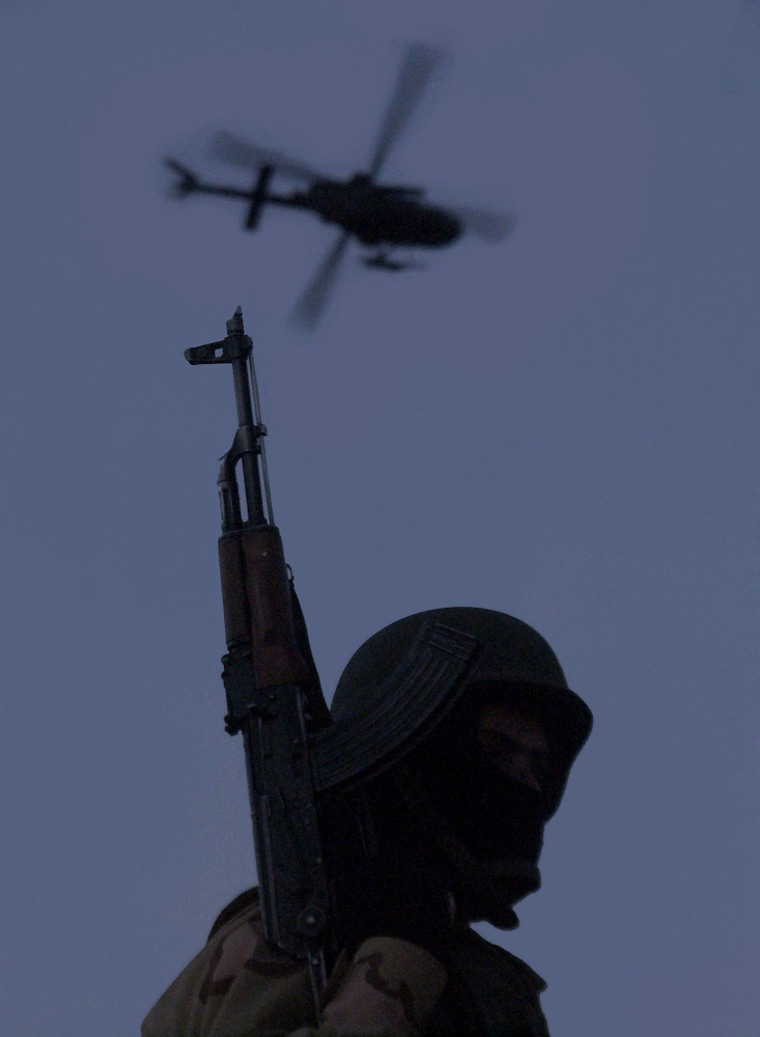 An Iraqi soldier is silhouetted against the sky as a U.S. helicopter flies overhead in Baqouba, Iraq, on Friday. As it did in 2005, the war in Iraq promises to dominate U.S. foreign policy in the upcoming year.