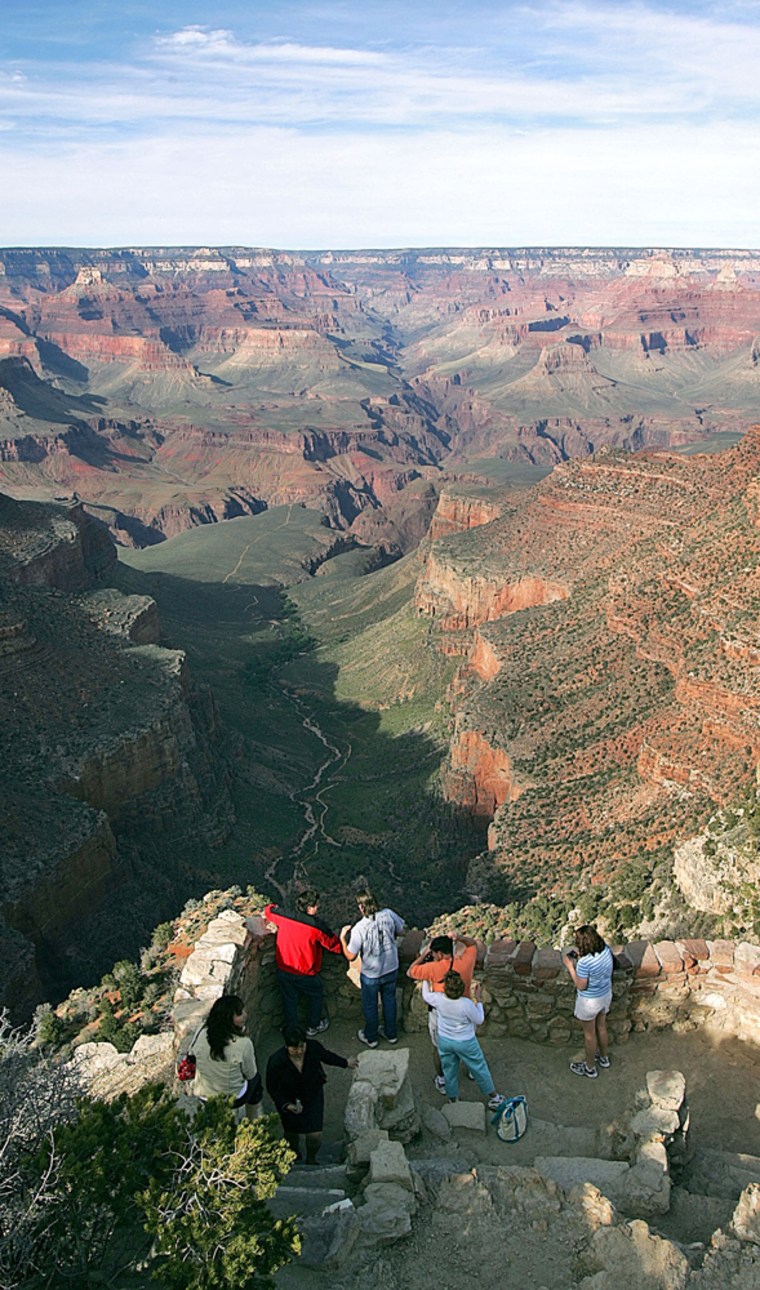 Tourists view the Grand Canyon's North Rim, where cattle grazing will be phased out after Wal-Mart provided grant money to buy two nearby ranches.