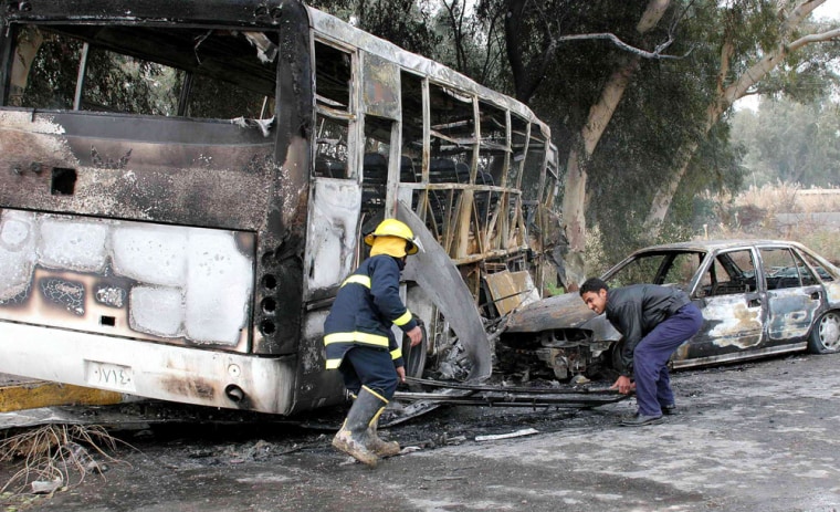 A burnt bus lies on the side of road with damaged civilian car in Baquba northeast of Baghdad