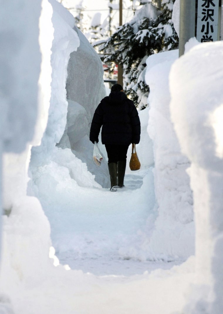 A woman walks along a path made through the snow in Tokamachi