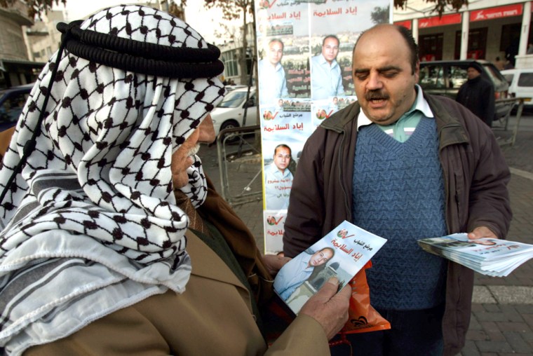 A Palestinian hands out an election campaign flyer to a prospective voter on Monday in Jerusulem, where Israel had threatened to prevent Palestinians from voting.