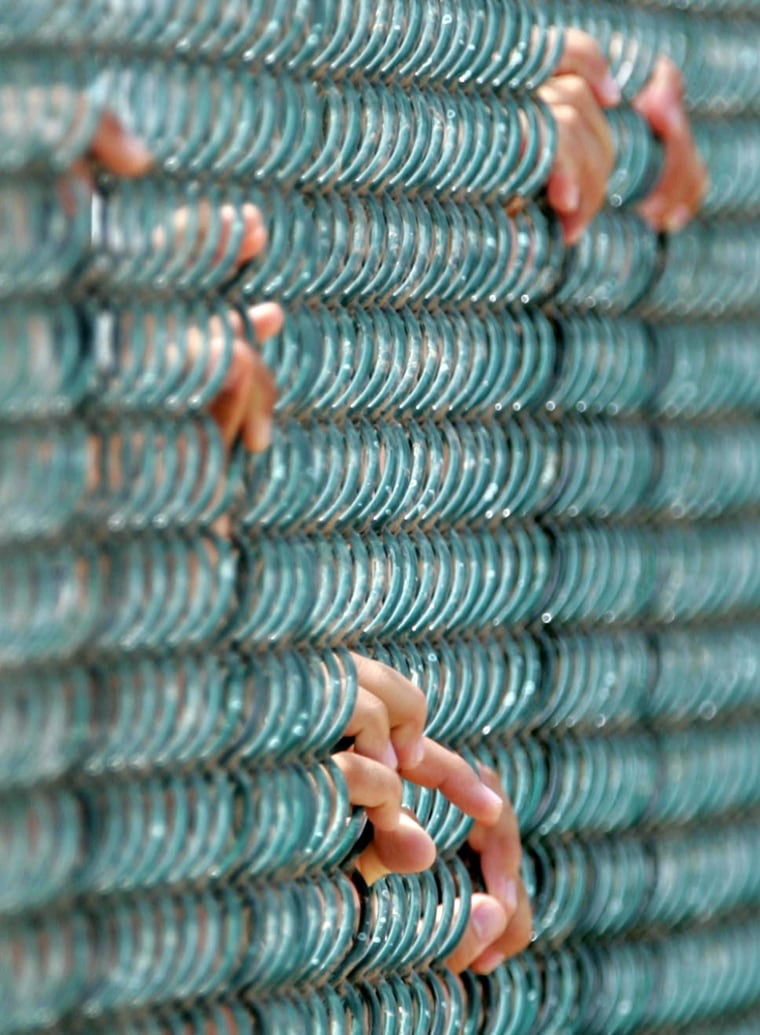 FILES - Detainee's hold onto a fence at