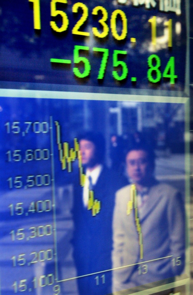 Businessmen look at the drop in stocks lit up outside a brokerage in Tokyo