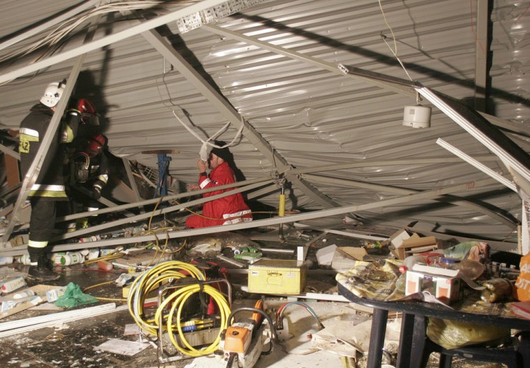 Rescue workers try to lift a collapsed roof of the Katowice International Fair building, in Katowice, southern Poland, Saturday, Jan. 28, 2006. The roof collapsed as an international pigeon fair was on, with hudreds of visitors inside. (AP Photo/Andrzej Grygiel PAP) **  POLAND OUT  **