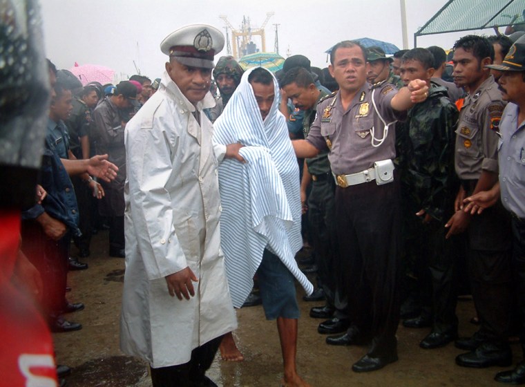 Indonesian police helps a survivor arriving in Tenau habour in Kupang after being evacuated from a ferry which sank near Rote island in Indonesia