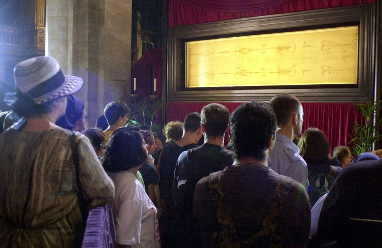 Pilgrims pray in front of the Shroud of Turin at the Cathedral of Turin, Italy, in this Aug. 12, 2000 file photo. Olympic tourists can go to the cathedral, but the closely guarded shroud won't be on display again until 2025.