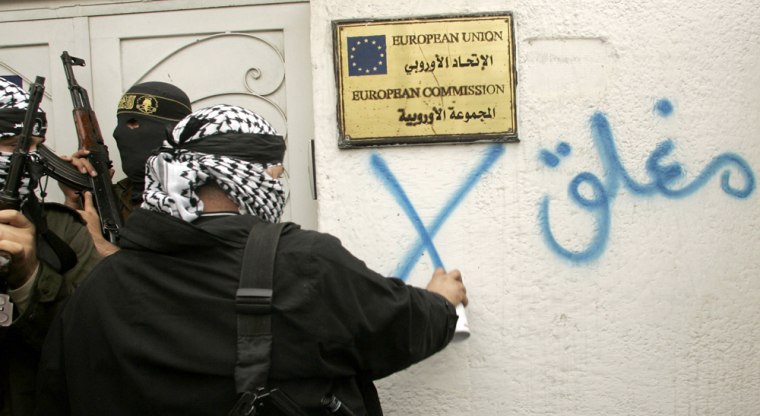 Palestinian Fatah gunman sprays the word \"Closed\" on wall of European Union headquarters in Gaza Strip