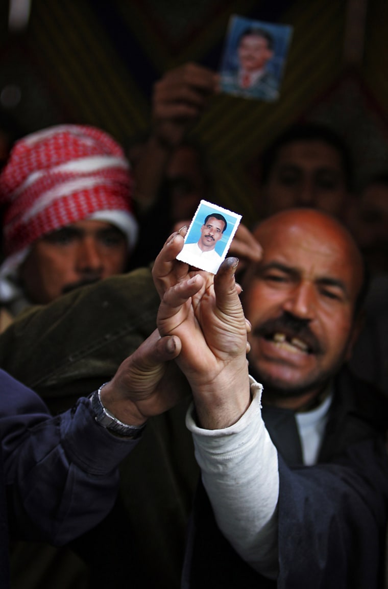 Egyptians hold up pictures of relatives missing after ferry disaster outside Red Sea port of Safaga in Cairo