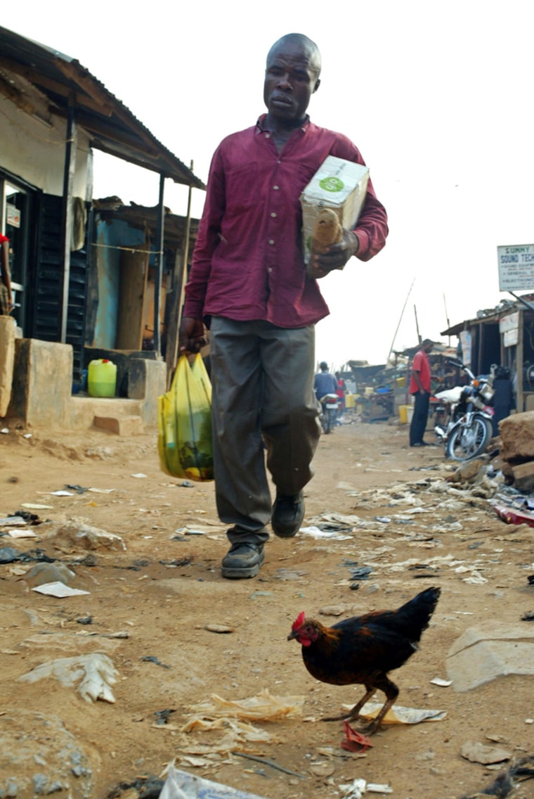 Nigerian man walks past chicken roaming on streets of Abuja
