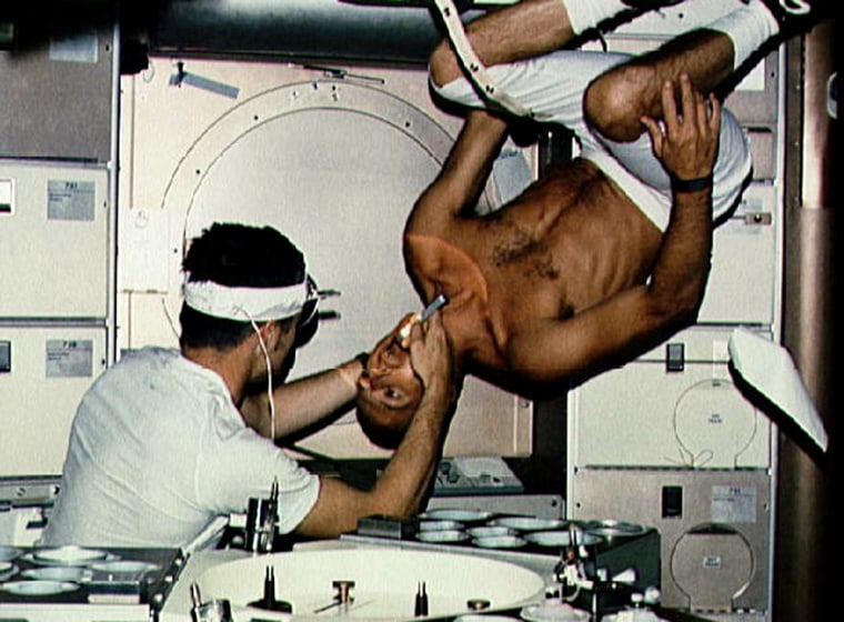 In this picture from NASA's Skylab in 1973, Dr. Joe Kerwin examines astronaut Charles \"Pete\" Conrad, Jr.