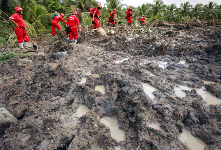 Members of a rescue team from Taiwan walk on rocks and mud after landslide buried Guinsaugon village in central Philippines