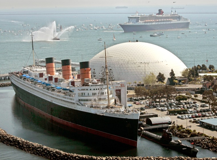 The Queen Mary 2, the world's largest ocean liner, top right, moves near its historic namesake the Queen Mary, docked below, Feb. 23, at the Long Beach Harbor, in Long Beach, Calif. 