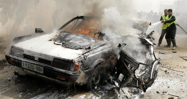 Palestinian civil emergency workers try to extinguish burning car after explosion in Gaza