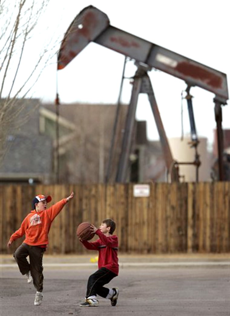 Children play near an oil pump in a housing development in Frederick, Colo. Tuesday, Feb. 14, 2006. Energy companies hunting for natural gas are snapping up land all around them, either through old oil shale claims or through federal auctions. (AP Photo/David Zalubowski)