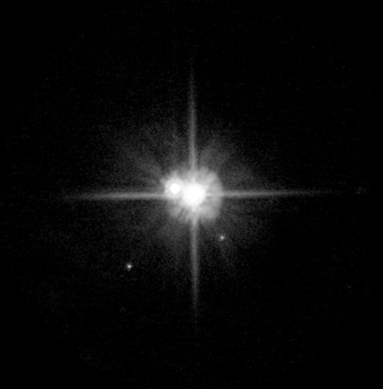 An image from the Hubble Space Telescope, captured March 2, shows Pluto and its largest moon, Charon, at the center — with two smaller satellites now known as Nix and Hydra appearing as specks farther out.