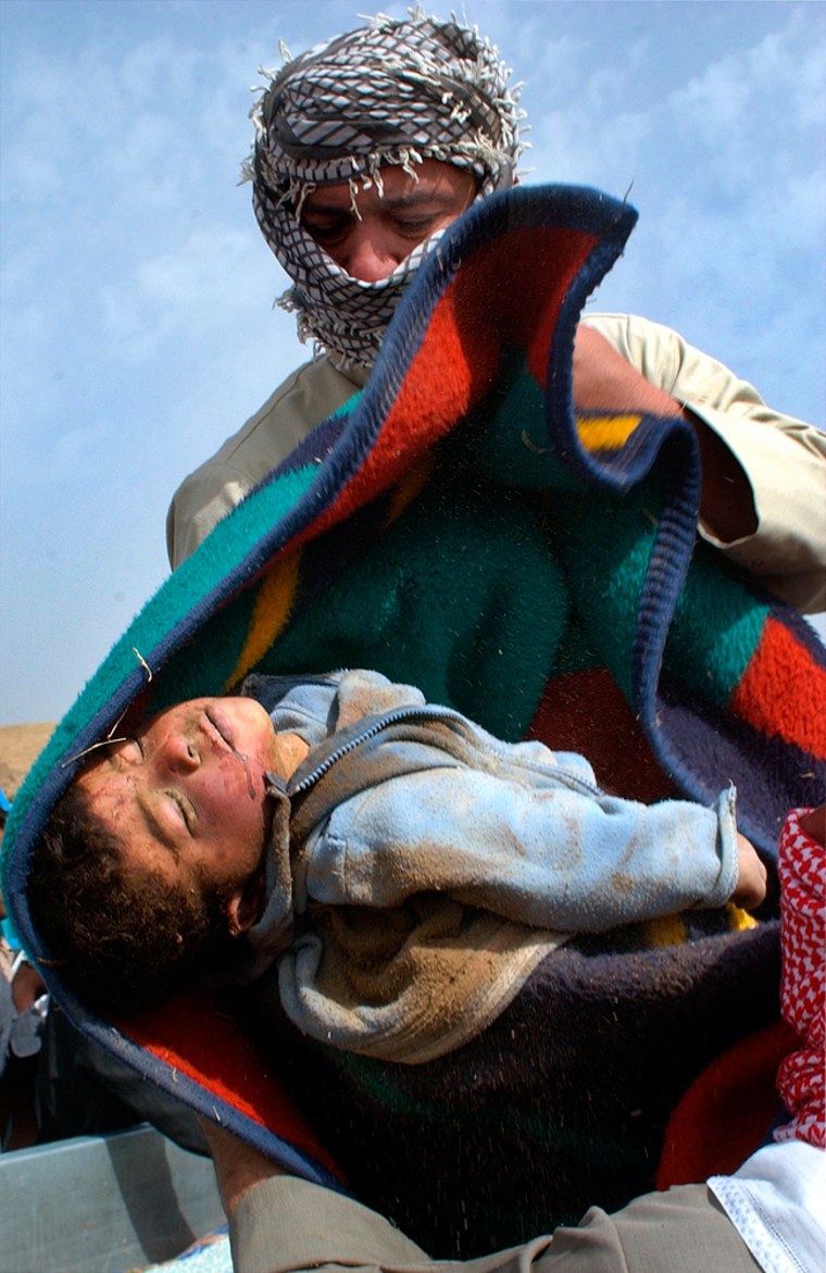 A relative carries the body of a child, reportedly killed during a U.S. raid in Isahaqi, Iraq, on Wednesday.