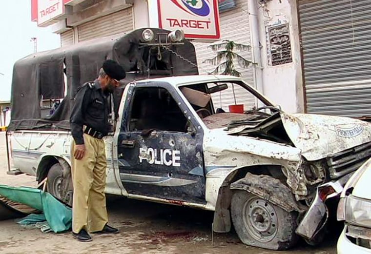 A Pakistani policeman inspects a damaged police vehicle in Pakistan