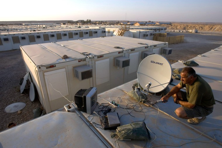 ** ADVANCE FOR TUESDAY MARCH 21 ** An Iraqi translator who works for the U.S. Marines, installs a satellite dish on the roof of his barracks at the al-Asad air base in Western Iraq, June 21, 2005. As the construction work goes on in full scale in Balad U.S. air base and handful of other installations, with Burger King and Pizza Hut already in, It is difficult to say weather U.S. forces in Iraq are here to stay for a short term or a long term. Nonetheless, if long term basing is on the horizon, there is no one to confer such plans. (AP Photo/Jacob Silberberg)