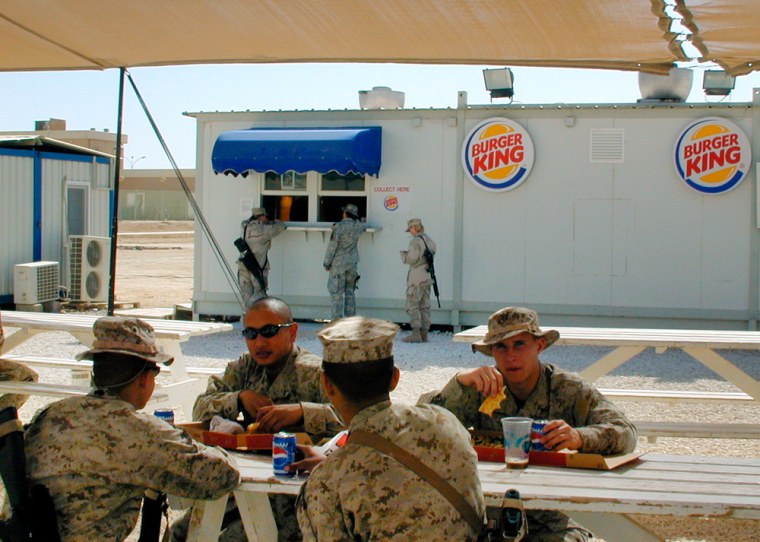 ** ADVANCE FOR TUESDAY MARCH 21 ** U.S. soldiers eat meals from Burger King, in al-Asad air base, 160 kilometers (100 miles) west of Baghdad,Iraq,march 4, 2006. As the construction work goes on in full scale in Balad U.S. air base and handful of other installations, with Burger King and Pizza Hut already in, It is difficult to say weather U.S. forces in Iraq are here to stay for a short term or a long term. (AP Photo /Charles J. Hanley)
