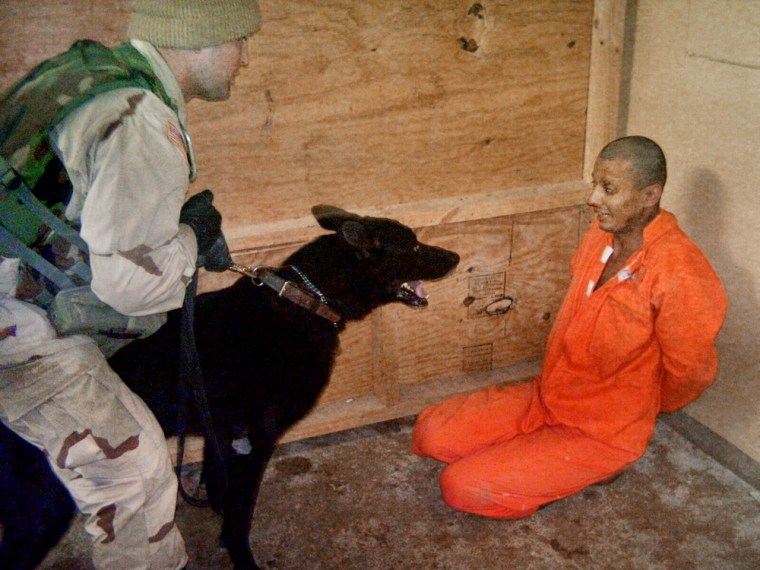 **FILE** This undated still photo made available by The Washington Post on Friday May 21, 2004, shows a U.S. soldier holding a dog in front an Iraqi detainee at Abu Ghraib prison on the outskirts of Baghdad.  (AP Photo/The Washington Post)