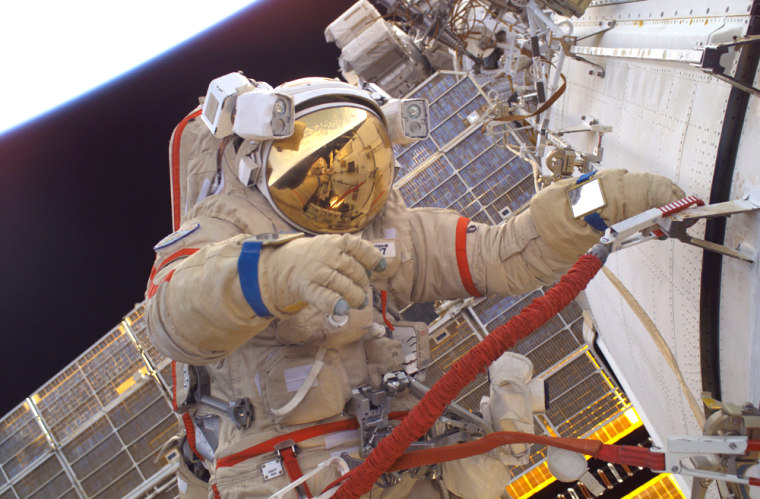 Dressed in a Russian spacesuit, NASA astronaut John Phillips takes part in a spacewalk at the international space station in August 2005. Such outings have to be put on hold until the station's crew members get more air-cleansing canisters for the suits.