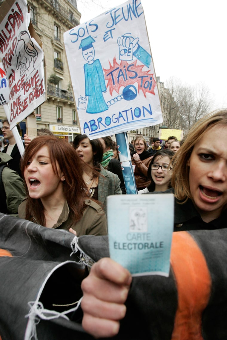 Students, one brandishing her voting card, right, march through Paris during a demonstration Thursday.