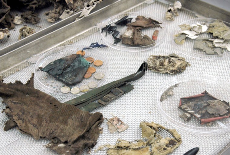 *** FILE *** Articles of clothing, coins and paper, found among the remains of a serviceman from World War II are shown on the examination table of the autopsy room at Joint POW/MIA Accounting Command (JPAC) at Hickam Airforce Base in Honolulu, Hawaii, Tuesday, Nov. 8, 2005. The World War II airman, now identified as Leo Mustonen, whose body was found on the California mountainside more than 60 years after his plane crashed will be buried in his central Minnesota hometown on Friday March 24, 2006. (AP Photo/Lucy Pemoni)