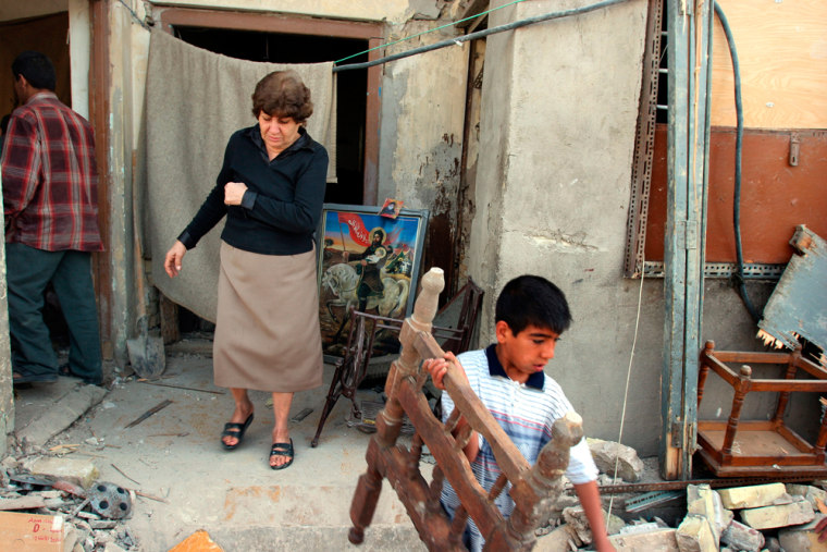 An Iraqi boy cleans the debris of his damaged house, following a bomb explosion, in Baghdad, Iraq, Sunday, March 26, 2006. A bomb exploded in front of a house in the central Baghdad Sunday, killing one woman and wounding two of her sisters and a man next door, police said. Elsewhere, a 13-year-old Iraqi student was killed after a roadside bomb exploded in front of a school Sunday in the city of Basra in southeast Iraq. Photographs of Imam Hussein, grand son of prophet Mohammed is seen. (AP Photo/ Karim Kadim)