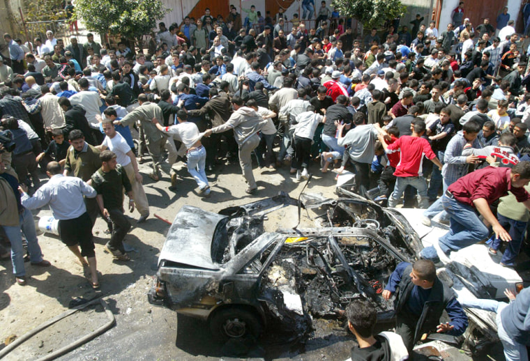 Palestinians run from car that exploded in Gaza