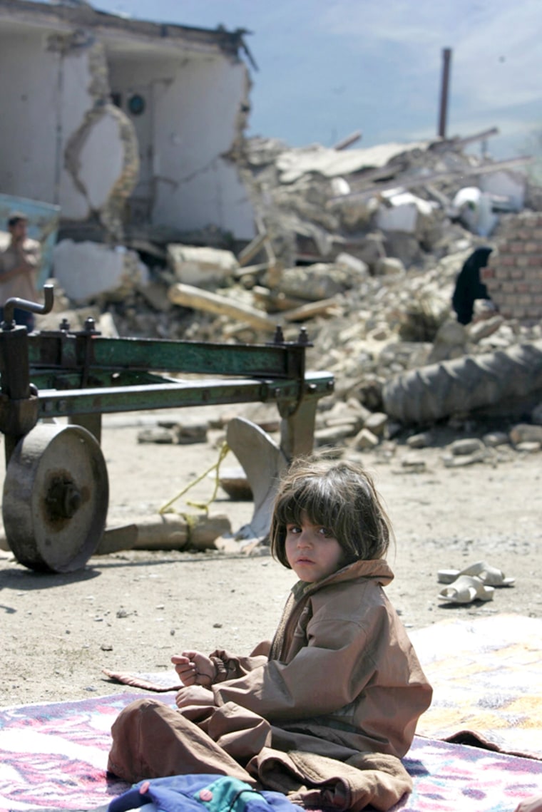 An Iranian girl sits on a blanket next t