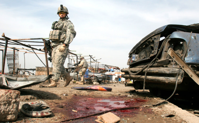 A U.S. soldier passes the bloody wreckage of a car bomb explosion in Baghdad on Tuesday.