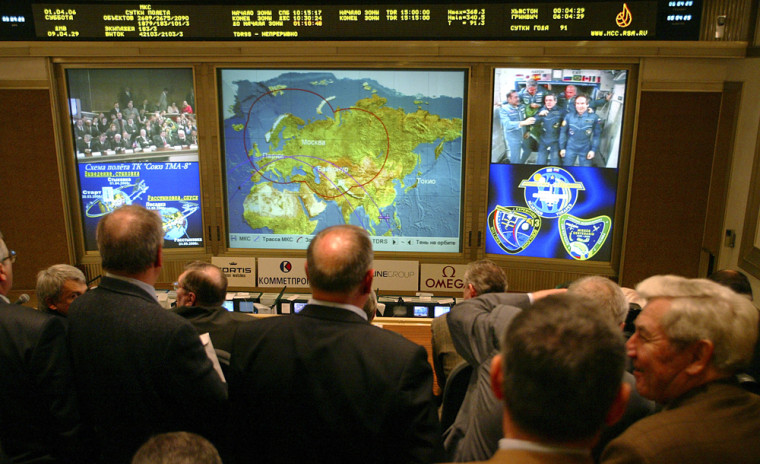 Officials and journalists at Russian Mission Control, near Moscow, watch screens showing the crew aboard the international space station.