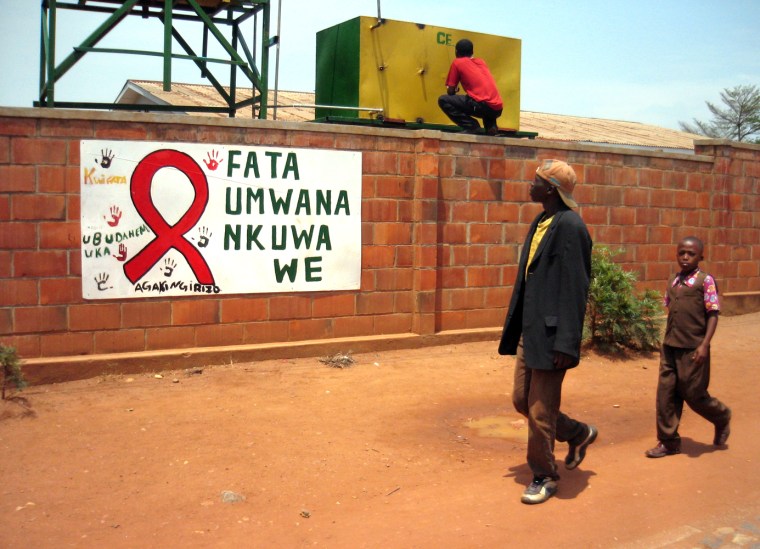 Passersby look at an AIDS awareness billboard in Kigali, Rwanda.