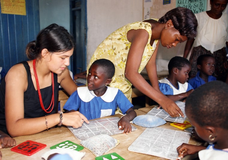 A volunteer with Cross-Cultural Solutions, left, and a local teacher help students with their lessons at a school in Ghana.