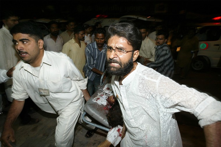 Volunteers move a wounded Muslim after a blast during a religious gathering in Karachi, Pakistan