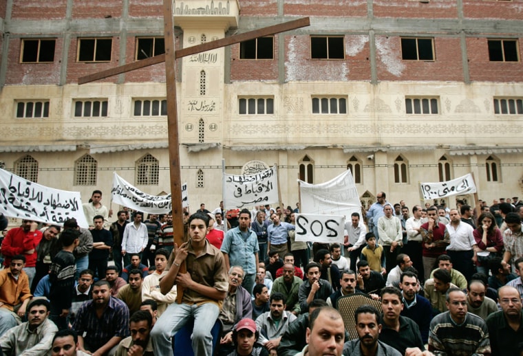 Angry Egyptian Copts, one holding a large wooden cross, gather outside the Saints Church in the Sidi Bishr district of Alexandria in Egypt on Friday. The violence came after a knife-wielding assailant attacked worshippers at Coptic churches in the northern Mediterranean city of Alexandria during Mass, killing one person and wounding at least five.