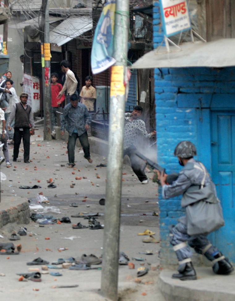 Nepali policeman fires a teargas shell at demonstrators at Chahabahil