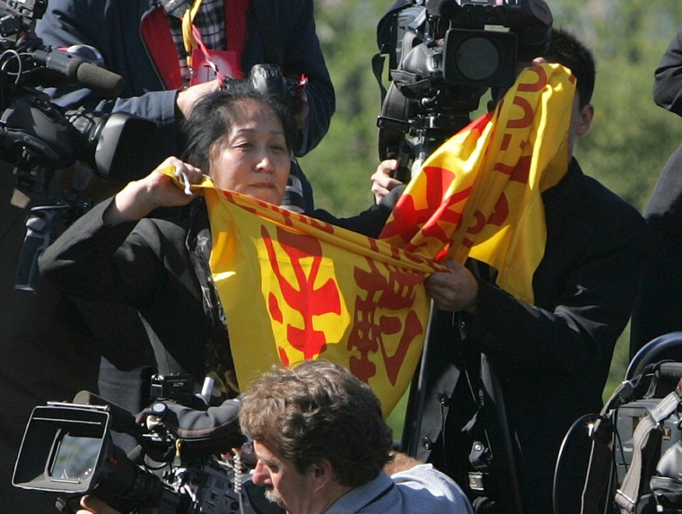 Protester Wenyi Wang, 47, shouts and tries to hold up a banner from her position on the camera stand as Chinese President Hu Jintao, not pictured, speaks during an arrival ceremony with President Bush on the South Lawn of the White House, on Thursday, April 20.