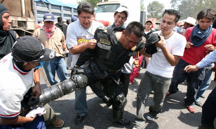 Villagers beat a police officer during clashes in the village of San Salvador Atenco