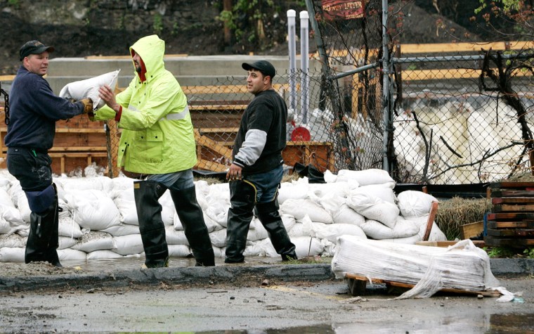 Workers pile sandbags along the Spicket River in Methuen, Mass., on Monday.