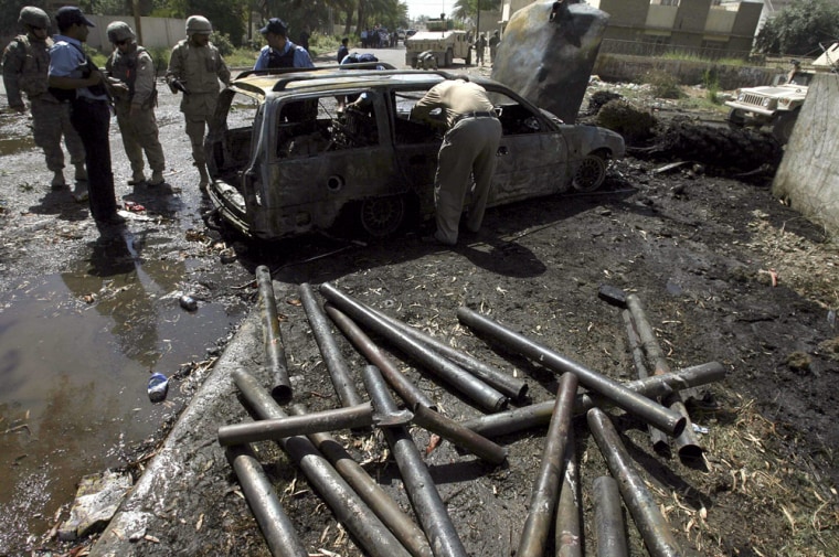 US soldiers and Iraqi police inspect remains of car, from which rockets were launched at interior ministry, in Zayouna neighborhood of eastern Baghdad