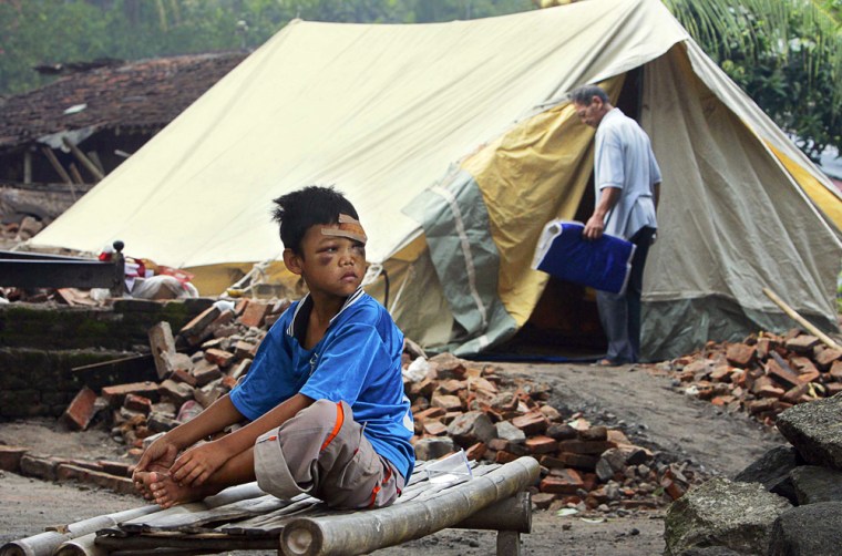 INJURED BOY SITS OUTSIDE TENT