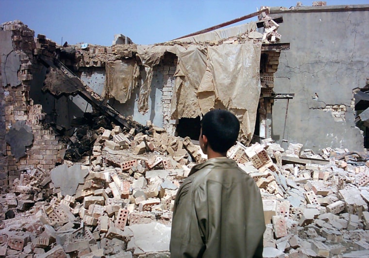 A boy stands outside a destroyed house after a U.S. raid in the village of Ishaqi